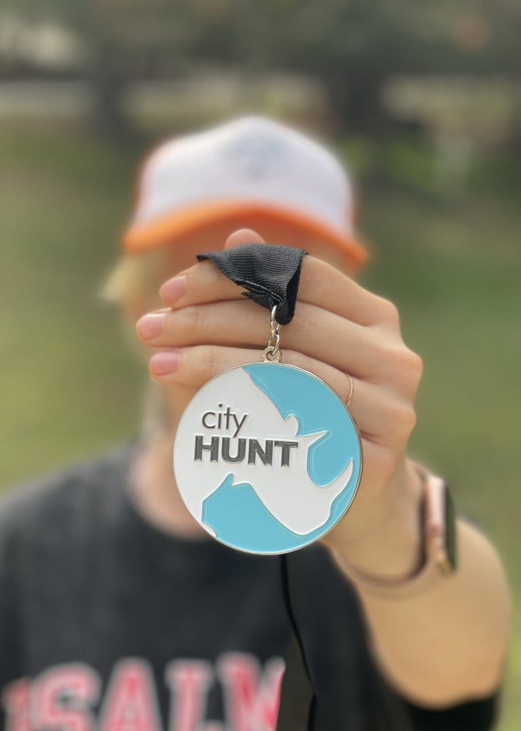 Person holding a cityHUNT winner medal on a black ribbon