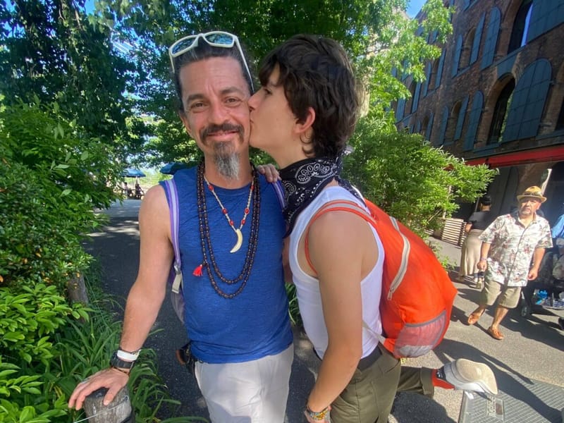 Ben Hoffman receiving a kiss on the cheek from his child outdoors on a sunny day